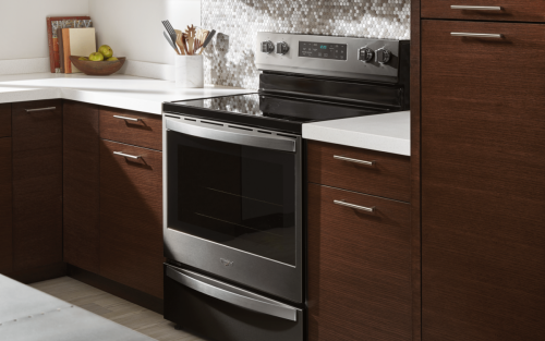 Silver and black electric stove surrounded by brown cabinetry