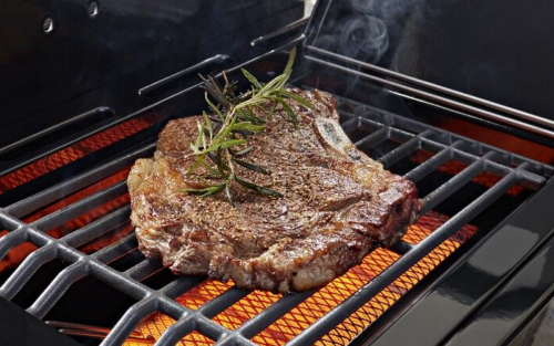 A garnished steak cooking over a grill