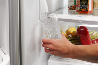 A person filling a glass of filtered water