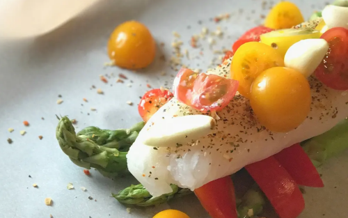 Steamed fish topped with sliced tomatoes