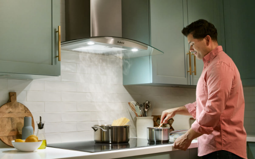 A man cooking pasta under a range hood