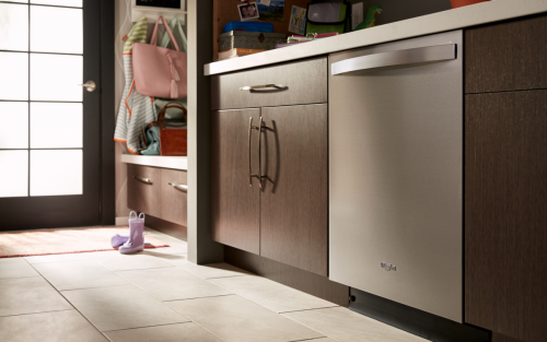 A Whirlpool® Top Control Dishwasher surrounded by brown cabinetry