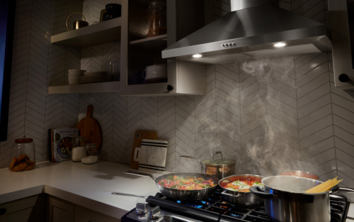 A range hood collecting the steam from various dishes cooking on a stovetop