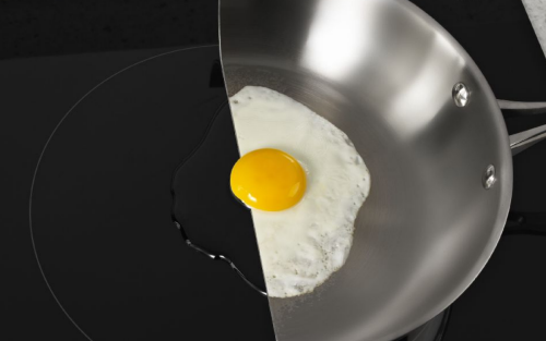 An egg cooking on a pan cut in half on an induction cooktop