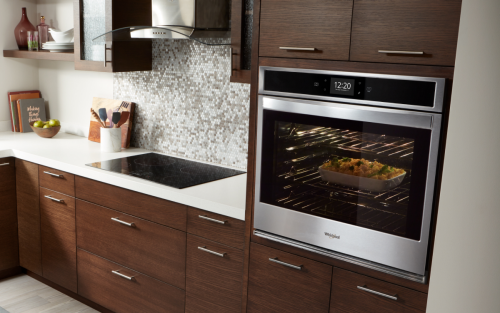 Whirlpool® oven set into wood paneling with casserole baking inside