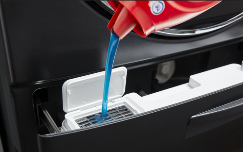 Closeup of blue liquid laundry detergent being poured into a washer detergent dispenser