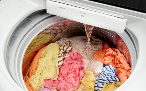A washer filled with clothing as water pours in