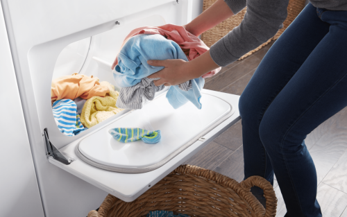 A person taking colorful clothes out of a dryer.