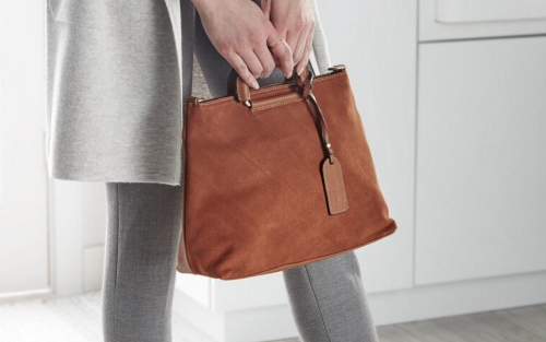 Person holding a suede handbag