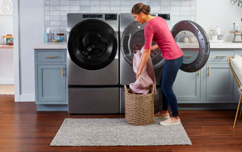 A woman preparing to dry a load of laundry using a Whirlpool® washer and dryer pair