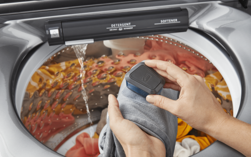 Person blotting oil stains from shirt before adding to washing machine