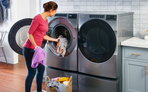 Person loading clothes into a front load Whirlpool brand washer