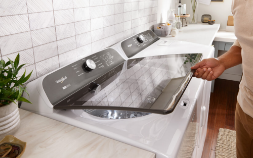 Person lifting the glass lid on a Whirlpool® Top Load Washer