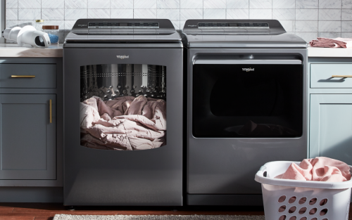 A blanket inside a Whirlpool® washer next to a Whirlpool® dryer in a modern laundry room.