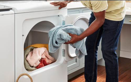 Person loading towel in dryer