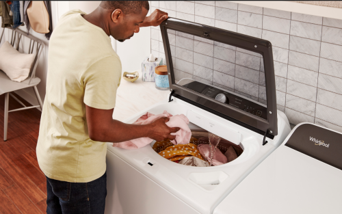 A man loading laundry into a top-load washer