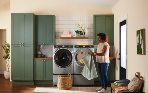 Person folding laundry in front of Whirlpool® Washer and Dryer pair on pedestals