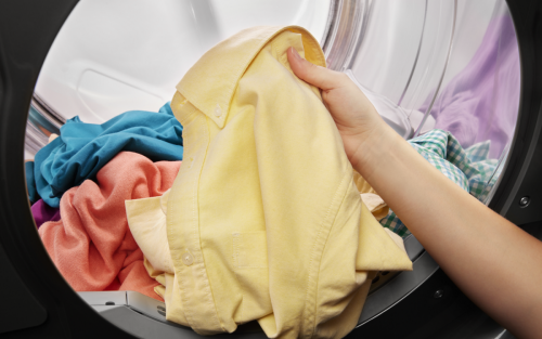 Person removing yellow shirt from dryer