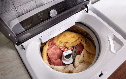 An open washing machine, filled with clothing