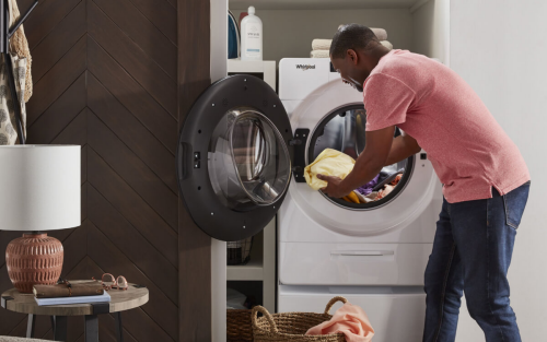 A person loading laundry into a Whirlpool® All-In-One Washer Dryer Combo