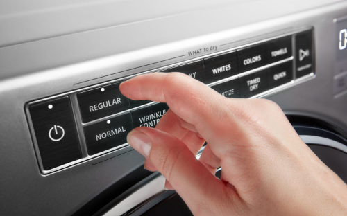 A person adjusting controls on a stainless steel dryer