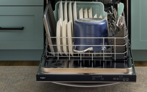The bottom rack of a dishwasher that is fully loaded