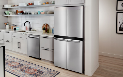 The inside of a kitchen with a counter-depth, stainless steel refrigerator