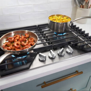 Shrimp and rice cooking in two pans on a gas cooktop