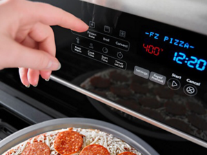 Hand about to select an oven setting on a gas stove control panel