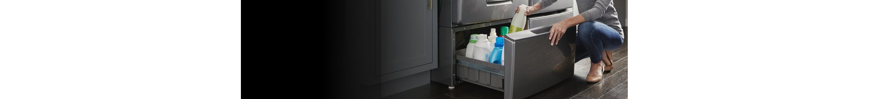Person organizing cleaners inside a laundry machine pedestal