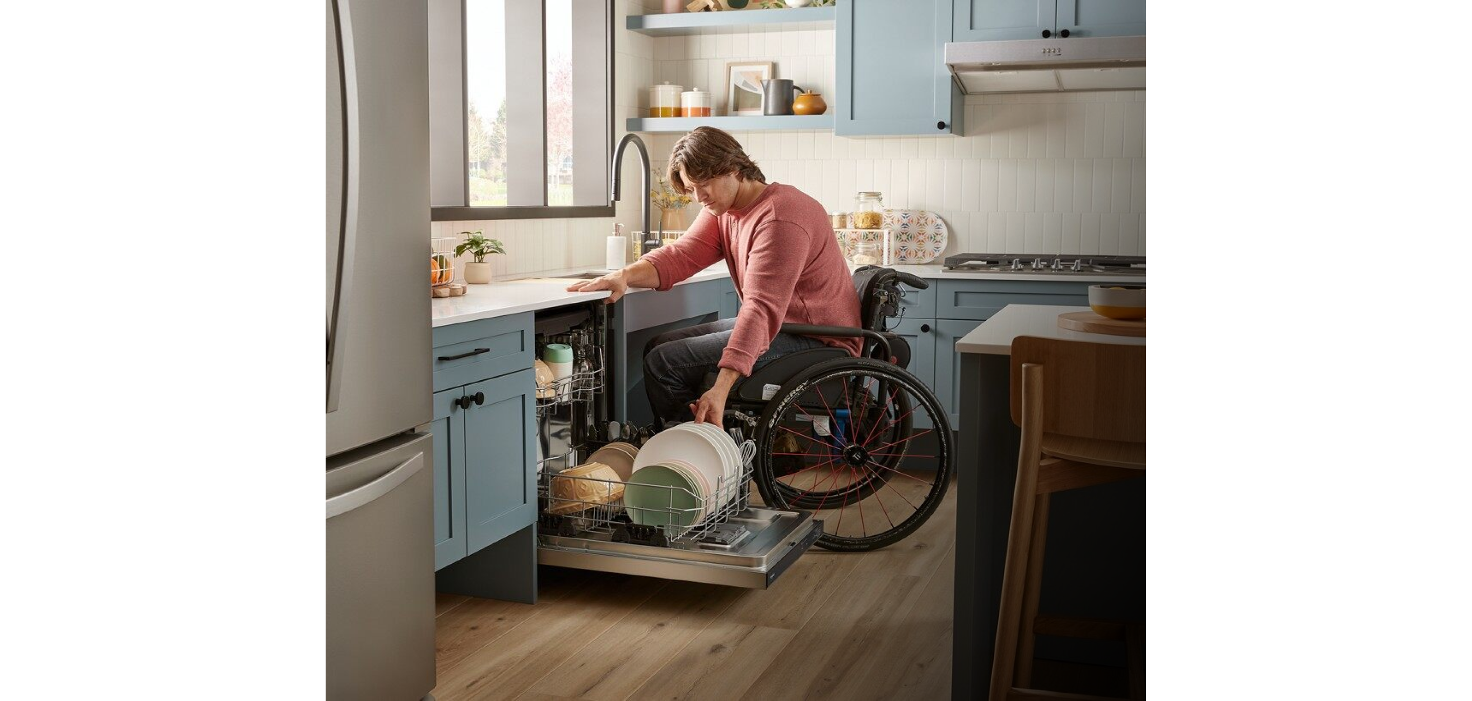 A person in a wheelchair unloading dishes from an ADA Compliant dishwasher