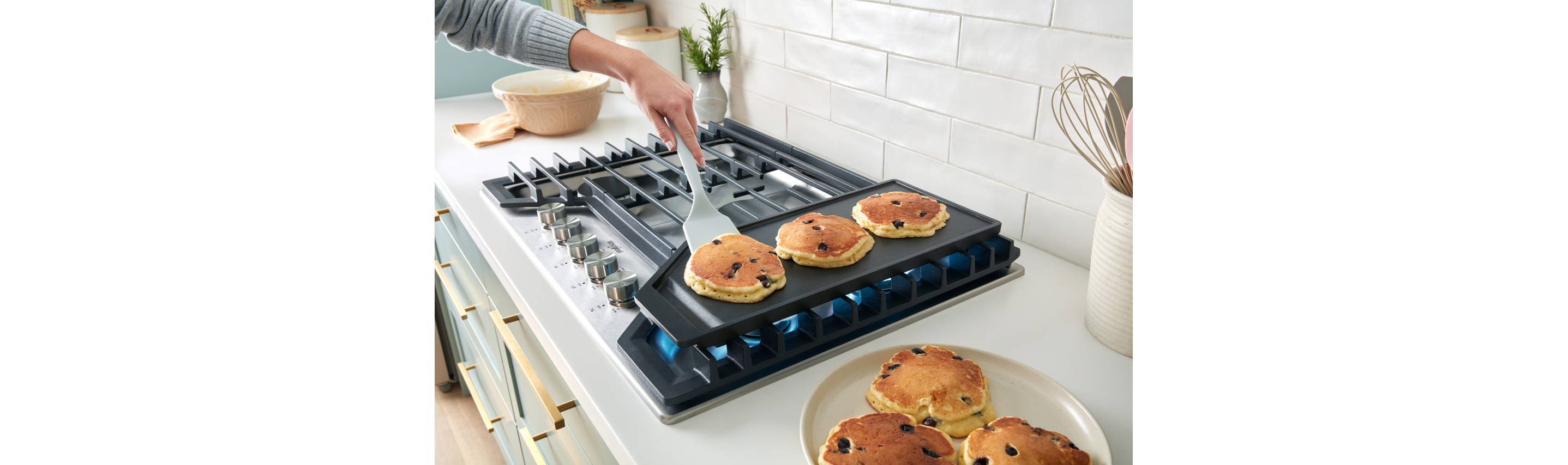 A person cooking pancakes on the griddle.