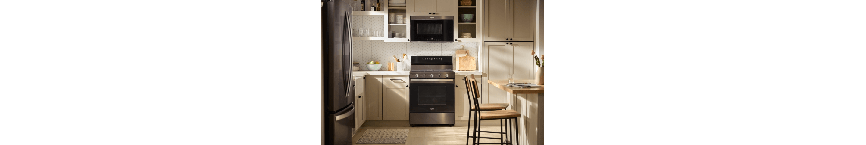 A Whirlpool® Freestanding Range and Over-the-Range Microwave in a kitchen with light taupe cabinets
