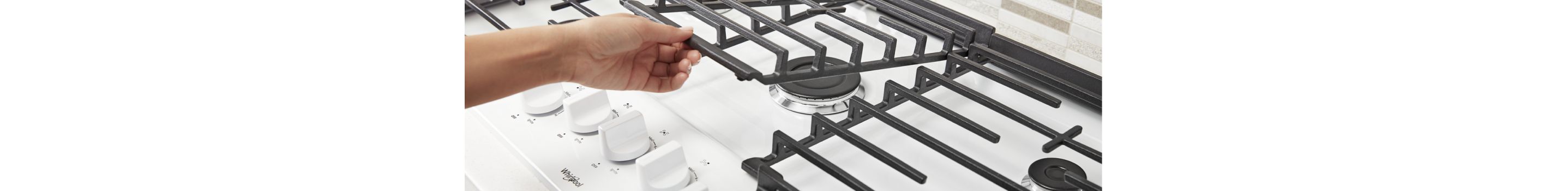 Hands lifting up the hinges on a Whirlpool® Gas Cooktop