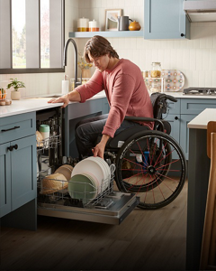 A man in a wheelchair loads a dishwasher