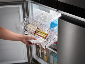A person pulling a drawer out of their freezer