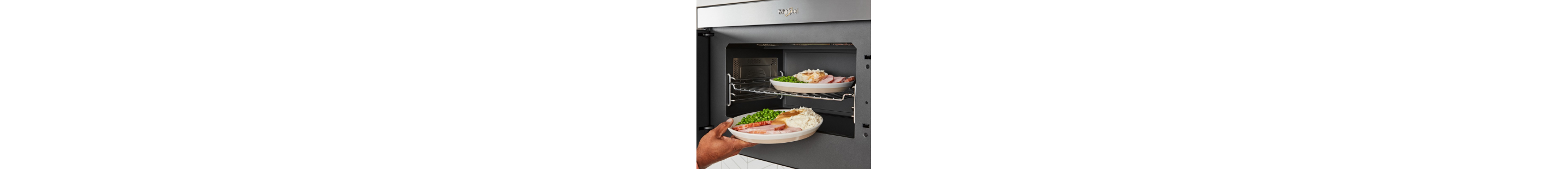 A person heating up two plates of food in a microwave