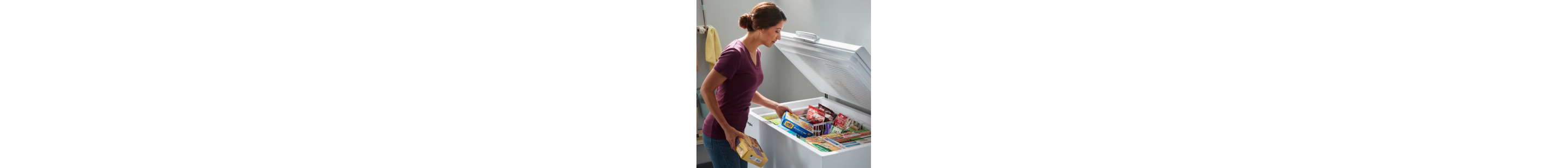 Woman placing food in white chest freezer baskets