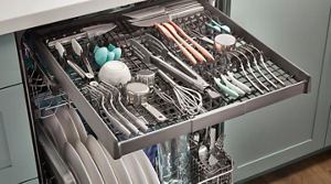 Loaded third dishwasher rack with organized silverware, utensils and measuring cups