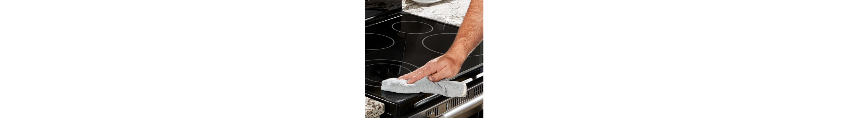 Person wiping down an electric stovetop with a rag