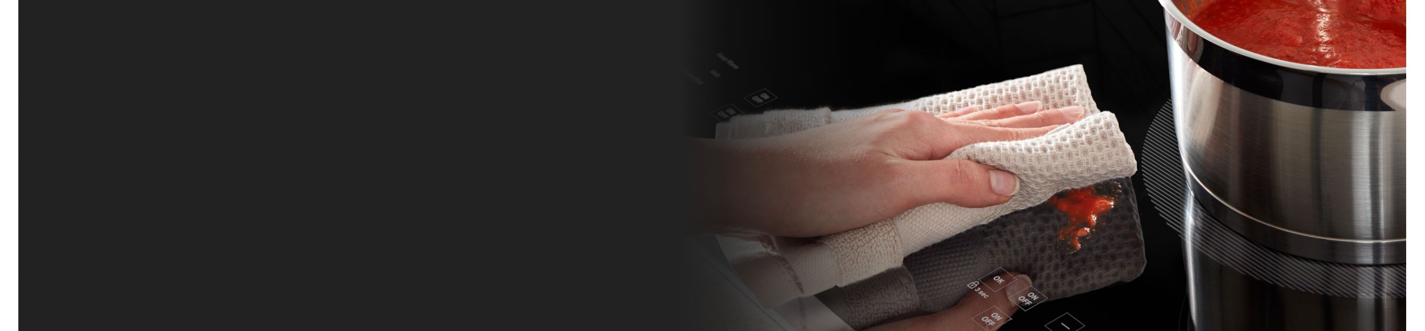 Person cleaning a Whirlpool® induction cooktop with a towel