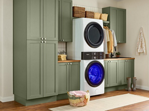 The inside of a well-organized laundry room with green cabinets and a stacked washer and dryer