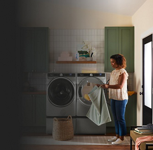 Person folding laundry in front of Whirlpool® Washer and Dryer pair on pedestals