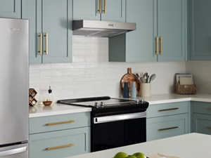 A kitchen with white counters and walls, blue cabinets, and a range hood over a range