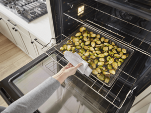 Someone pulling a tray of vegetables out of their oven