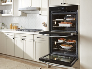 A double wall oven, with both doors open, full of various pans of food