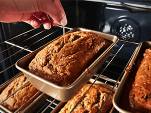 Someone using a toothpick to test the doneness of bread in an oven
