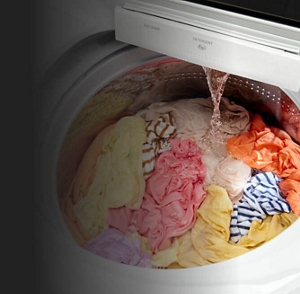 A washer filled with clothing as water pours in