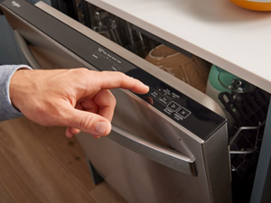 A person using their finger to choose a dishwasher cycle