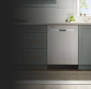 A closeup of a stainless steel dishwasher in a kitchen with green cabinetry